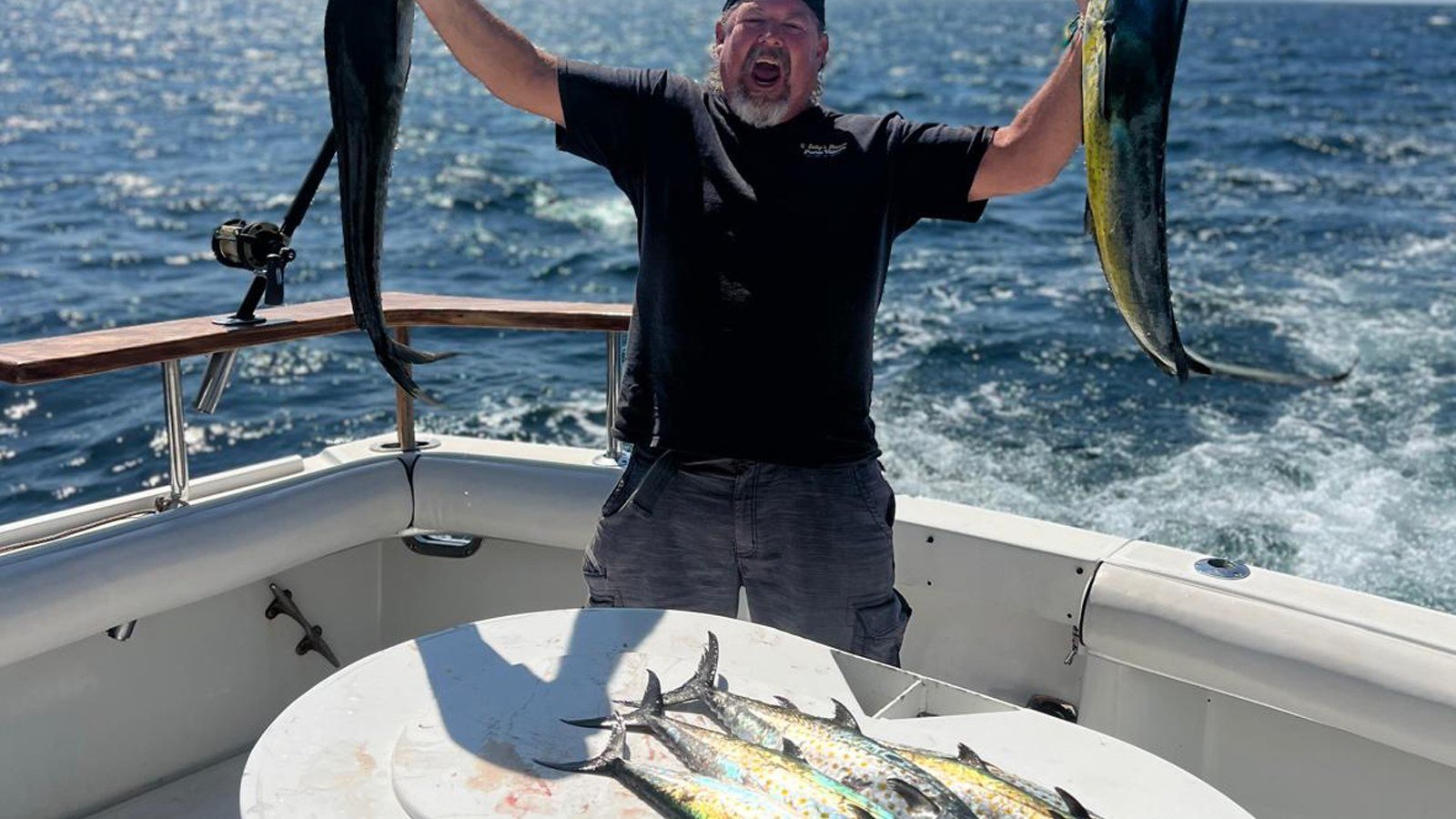 A happy angler holding up two dorado on a Puerto Vallarta fishing charter, the fish most first-timers bring home