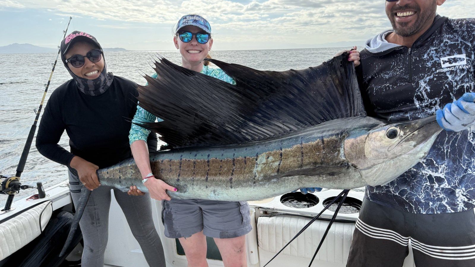 Three anglers holding a sailfish before releasing it on a fishing charter off Puerto Vallarta